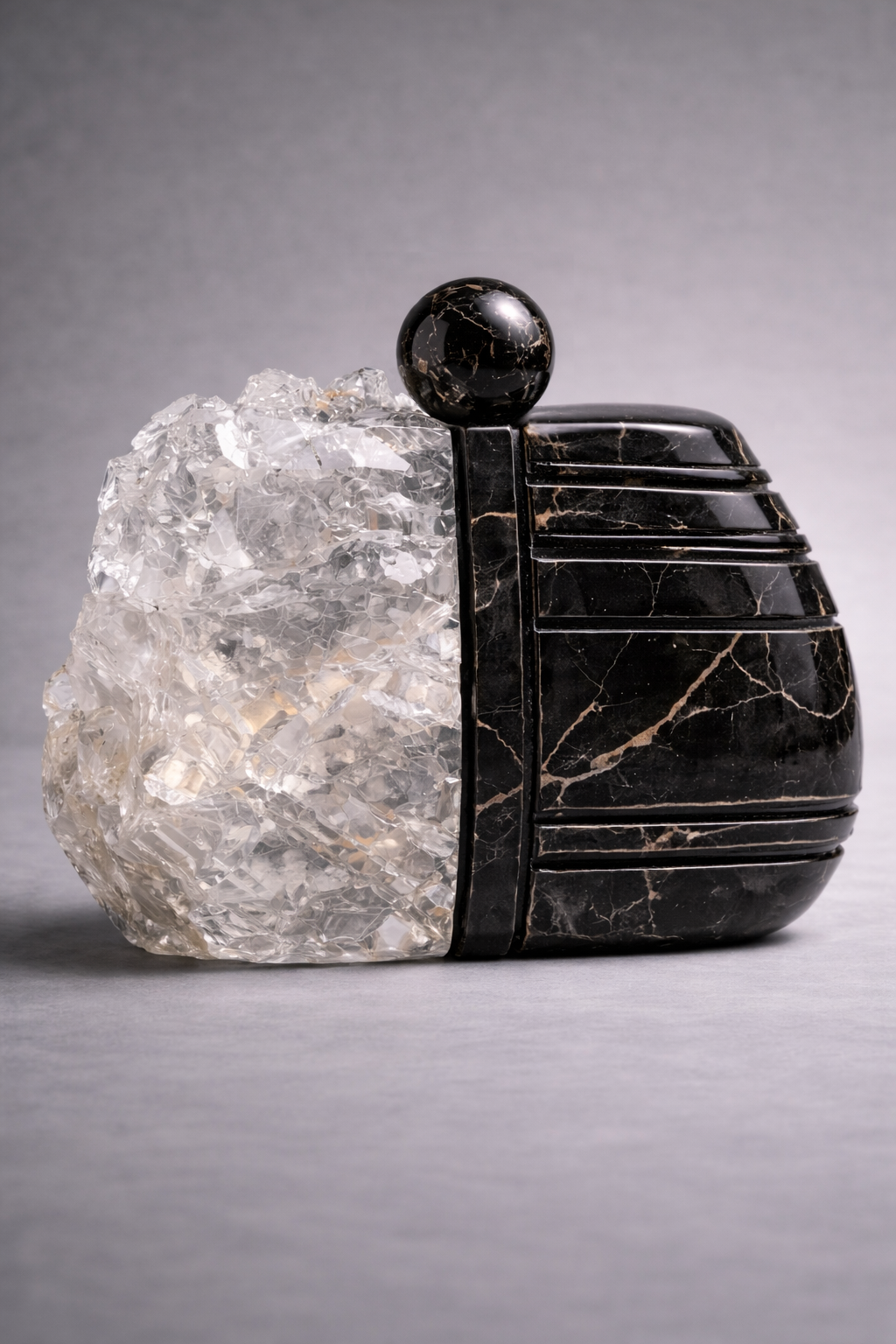 Black stone clutch bag with a crystal accent on a gray background