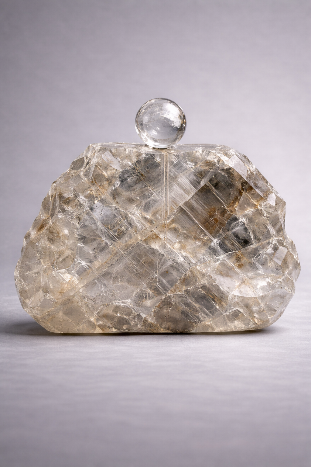Crystal clutch bag made of natural rock crystal on a gray background