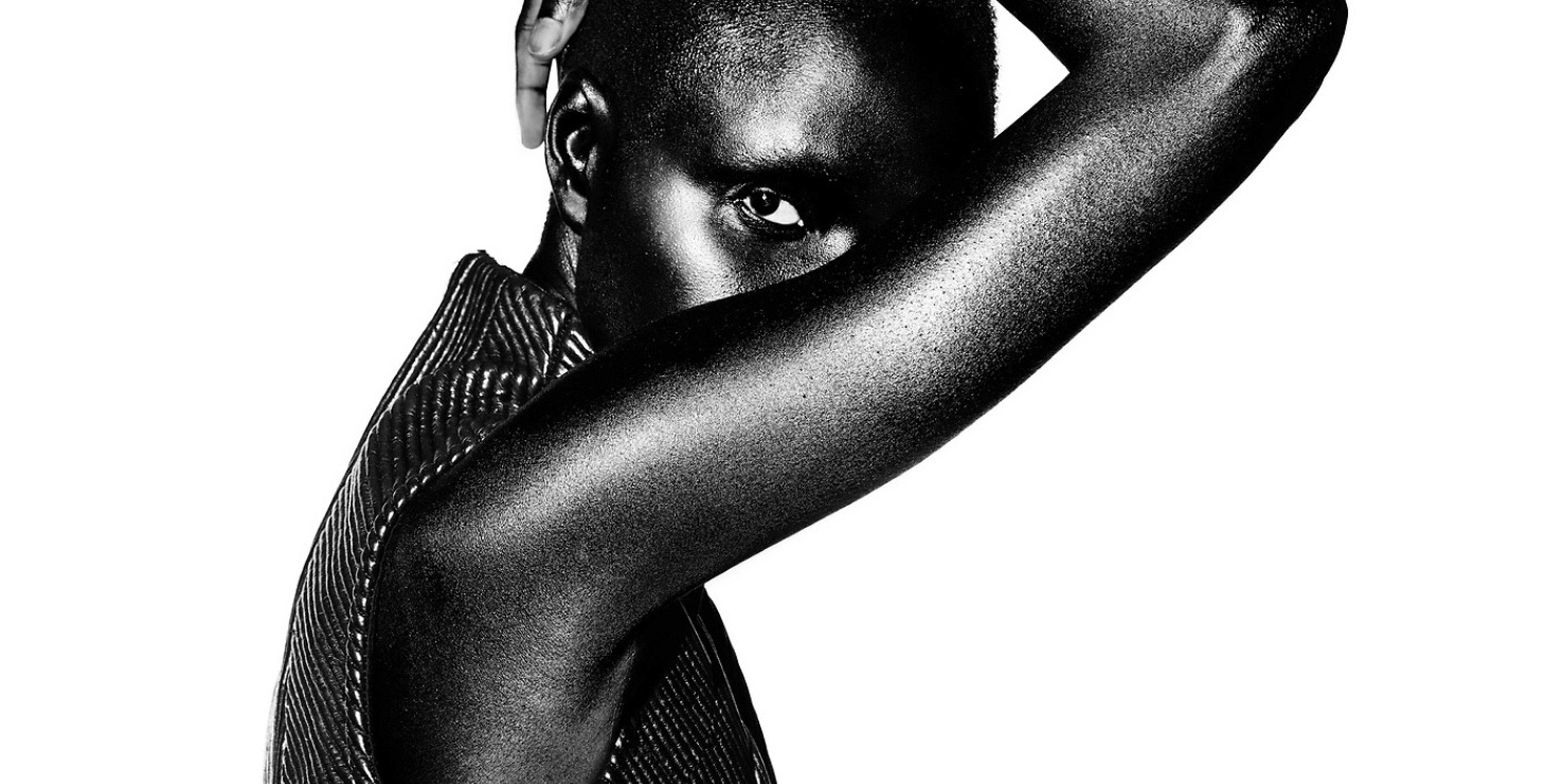 Black and white portrait of a person with one arm covering their face on a white background