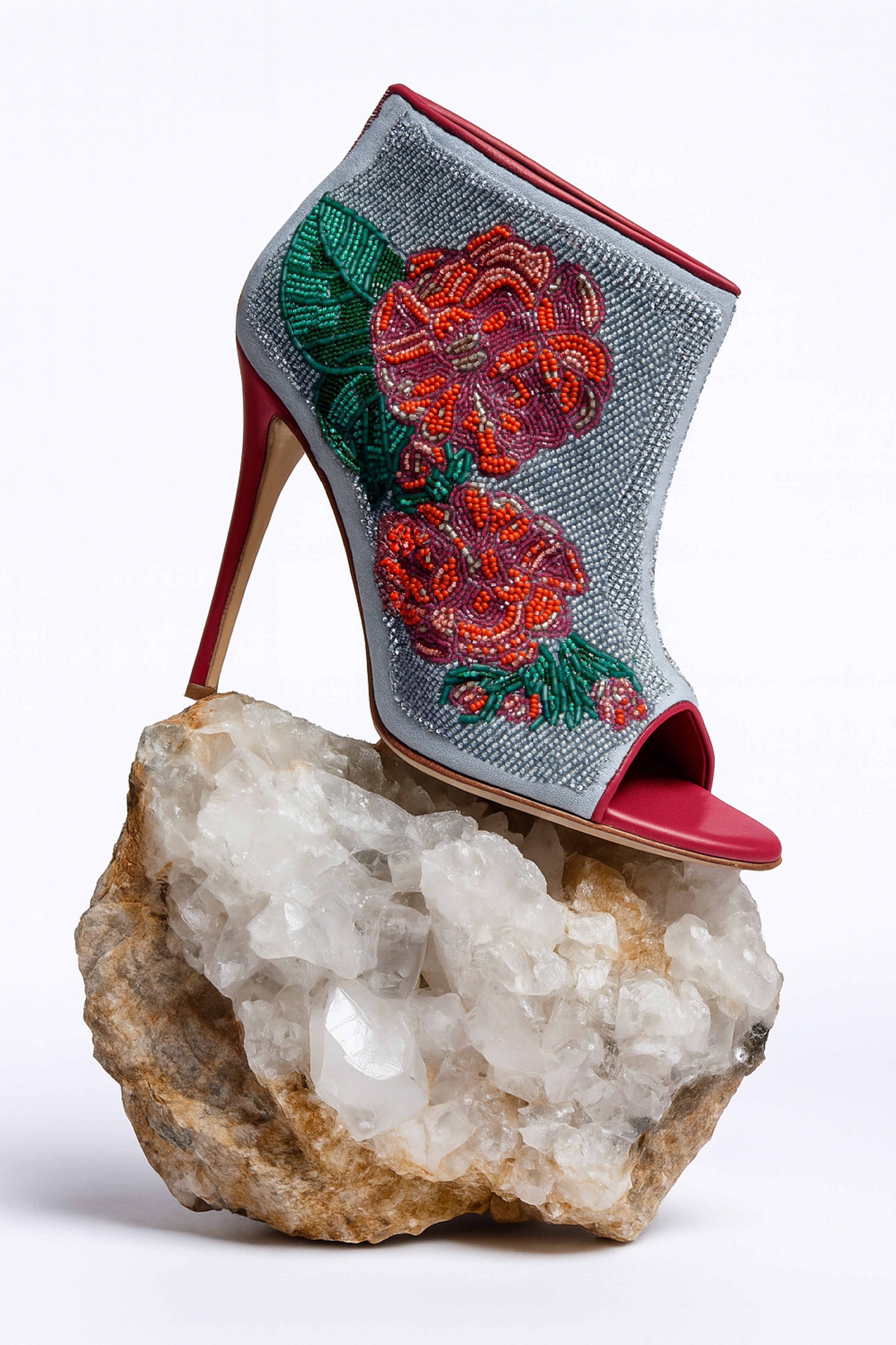 High-heeled shoe with floral beaded design on a rock
