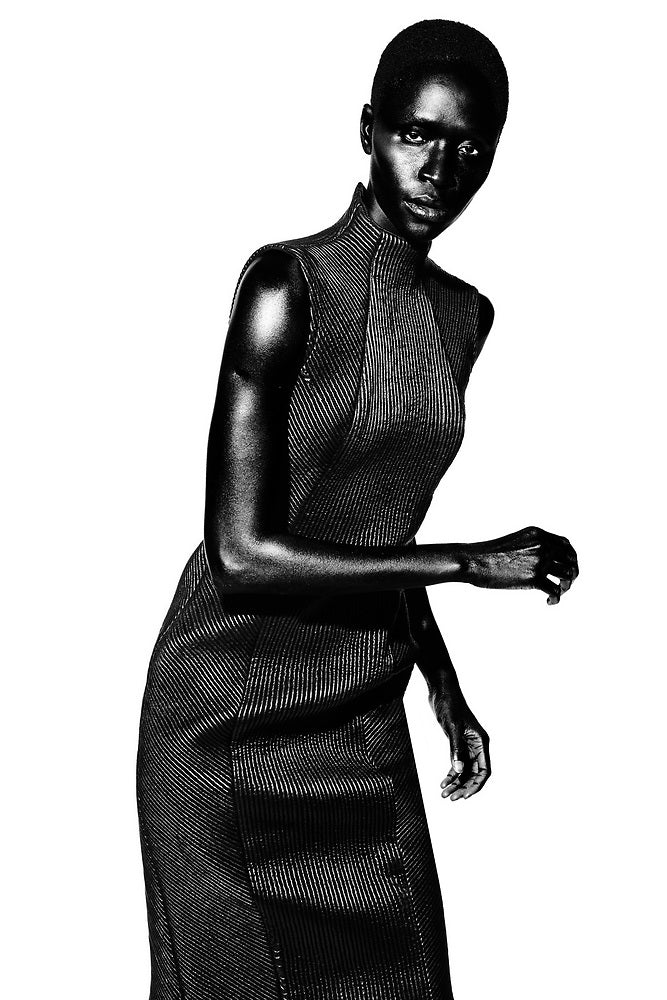 Black and white portrait of a model wearing a sleeveless leather quilted and embroidered sheath dress.