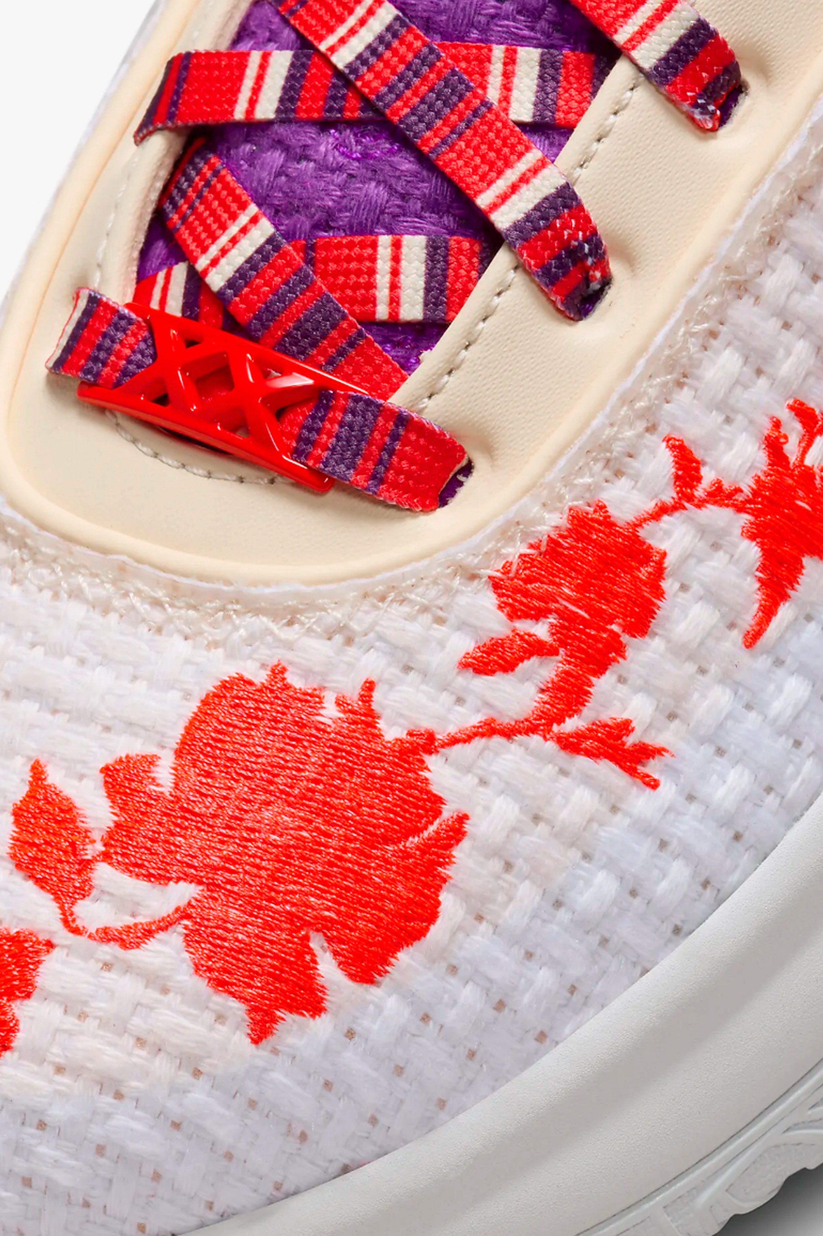 Close-up of a basketball shoe with red floral embroidery and colorful laces.