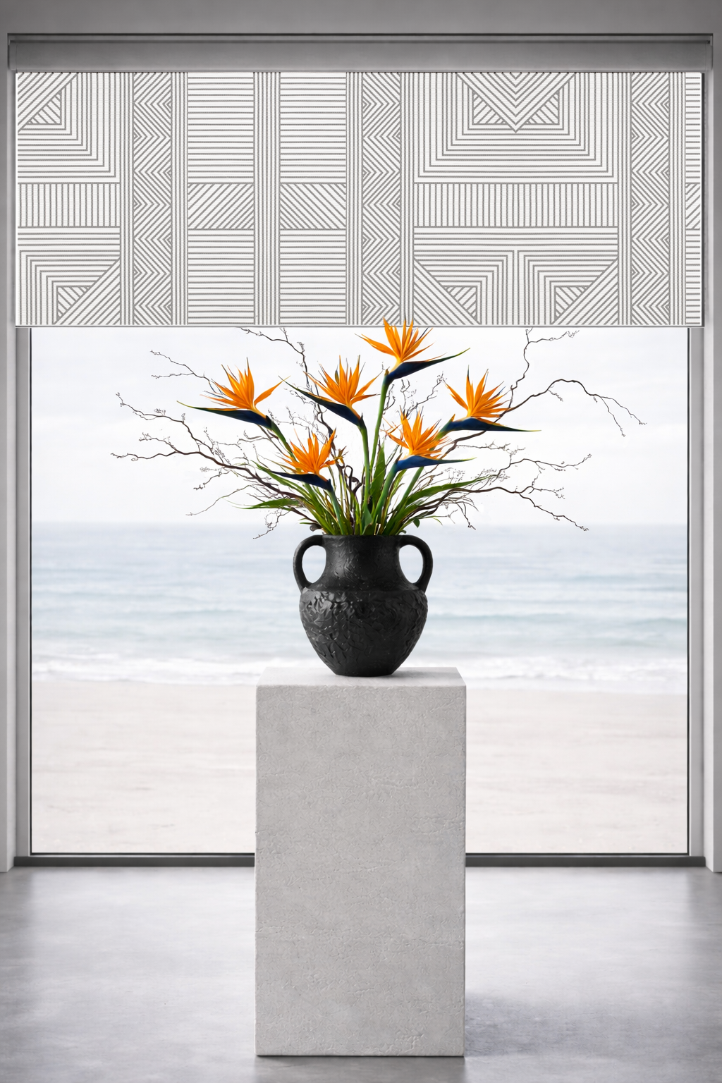 Decorative roller shades with a geometric pattern and a vase with flowers on a pedestal.