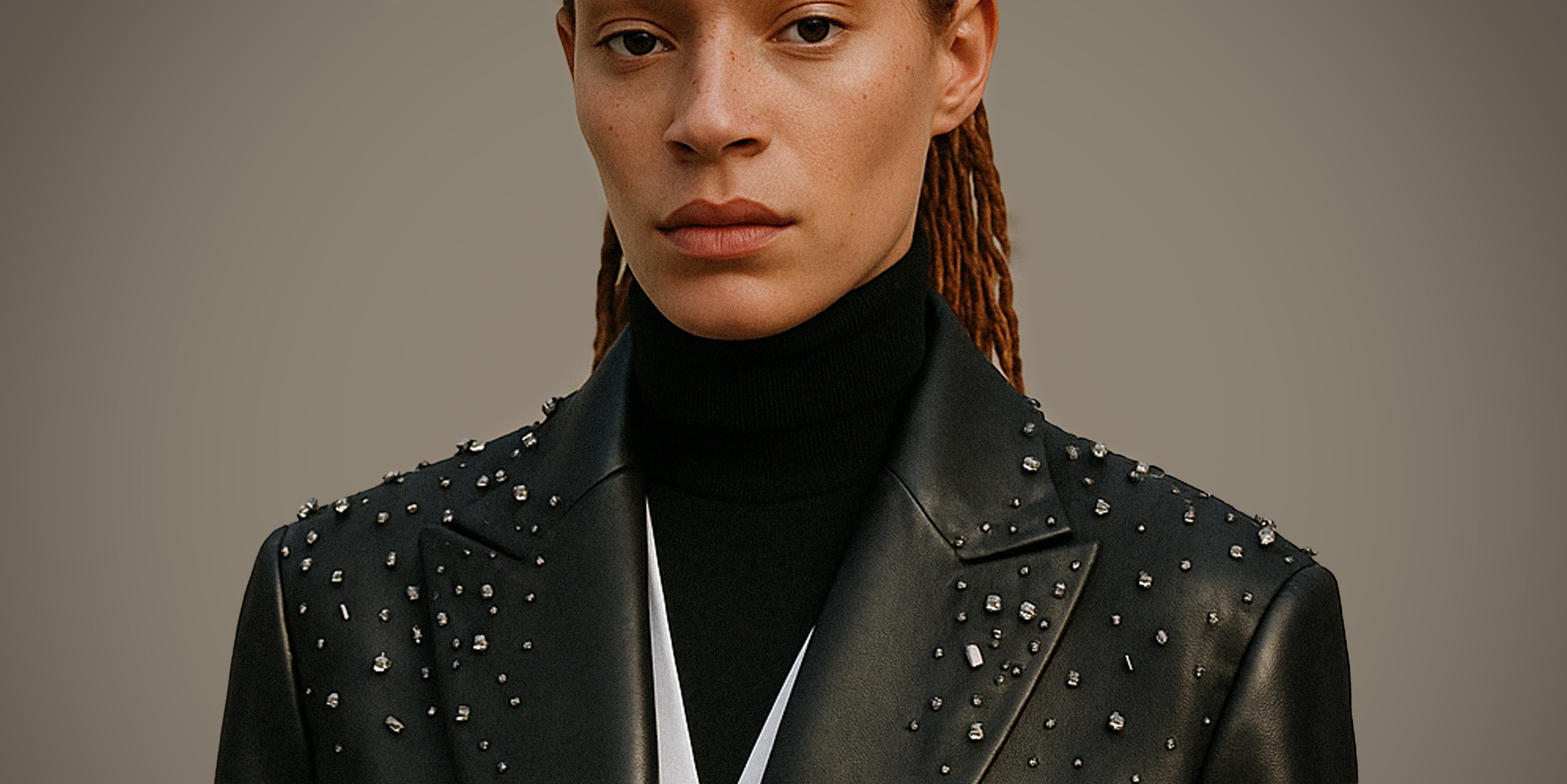 Person wearing a black studded leather blazer jacket against a neutral background