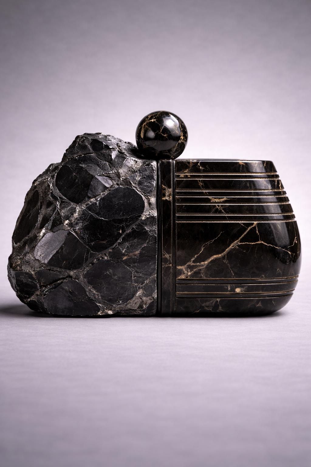 Carved black stone clutch bag with contrast sides on a neutral grey background