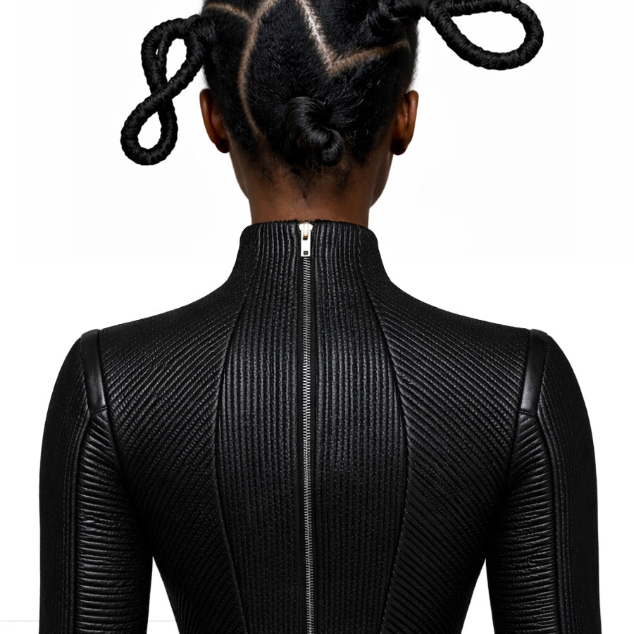 A woman wearing a black leather trapunto embroidery textured outfit with a zipper on a white background