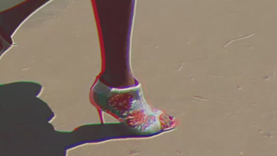 A woman walks wearing Manolo Blahnik x Mimi Plange hand embroidery booties, heels
